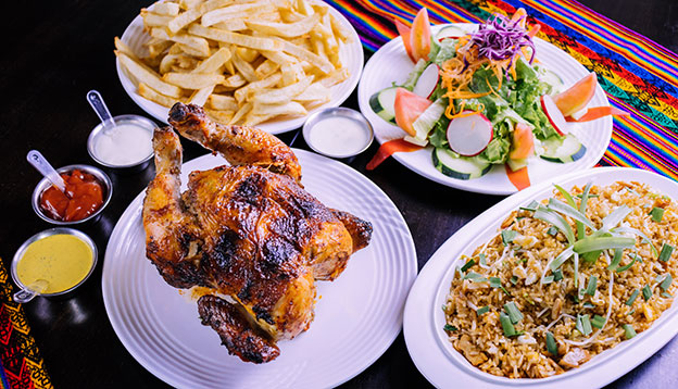 Pollo a la brasa - Peru roasted chicken served with salads and chips on a table pollo a la brasa - Peru roasted chicken served with salads and chips on a table