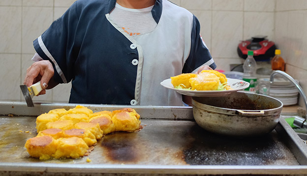 A cook preparing llapingachos - a typical dish from the central Andean region of Ecuador. A cook preparing llapingachos - a typical dish from the central Andean region of Ecuador.