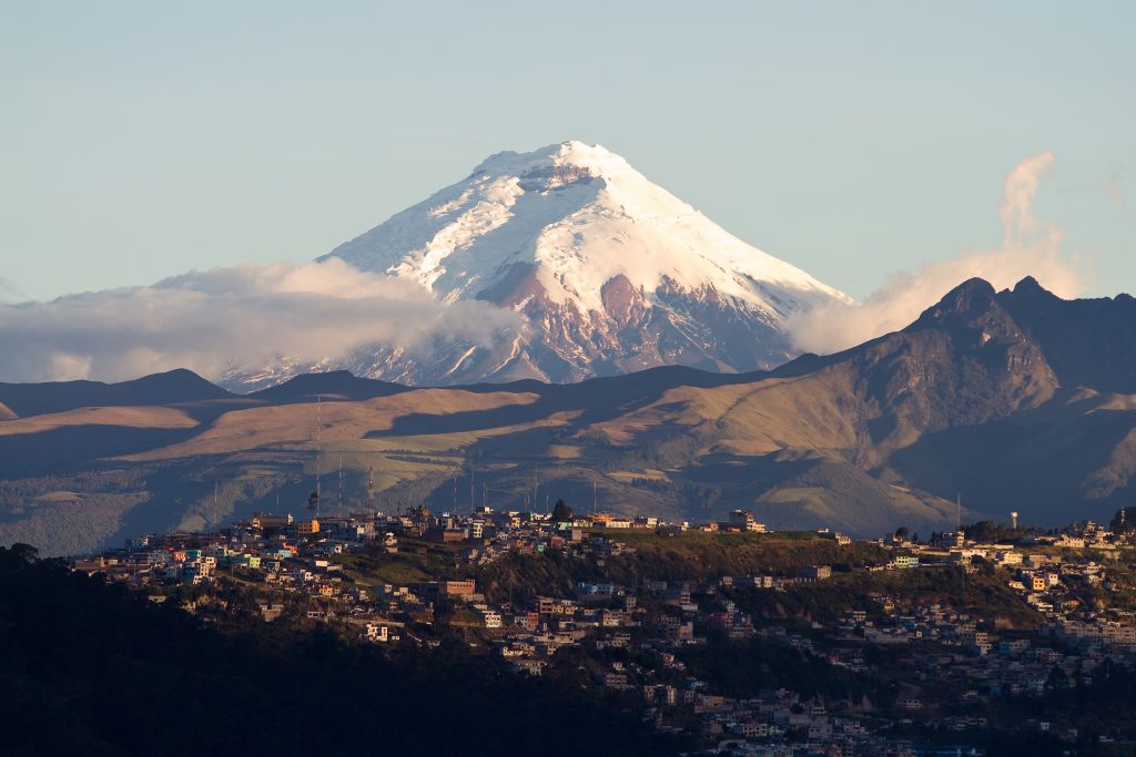 Cotopaxi volcano on the background, and the city on the front Cotopaxi volcano on the background, and the city on the front