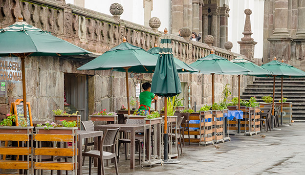 a restaurant with green huge umbrellas and chairs located in the historical centre of old town Quito a restaurant with green huge umbrellas and chairs located in the historical centre of old town Quito