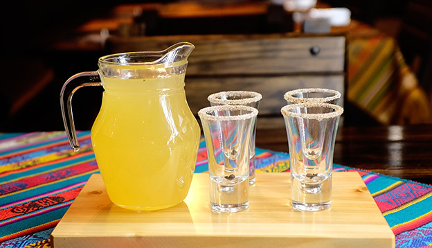 A jug of Canelazo with 4 glasses on a table A jug of Canelazo with 4 glasses on a table