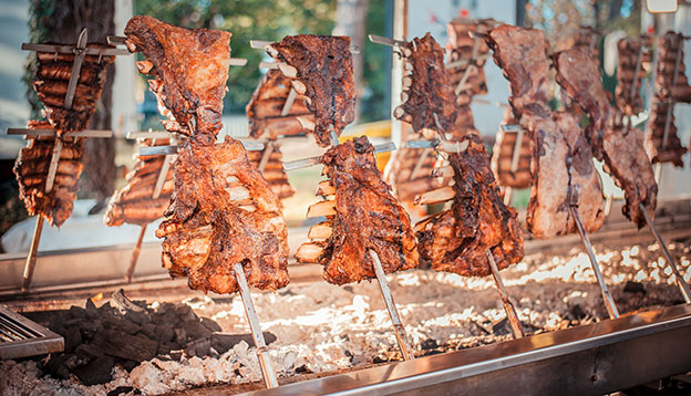 Asado, traditional barbecue dish in Argentina, roasted meat of beef cooked on a vertical grills placed around fire Asado, traditional barbecue dish in Argentina, roasted meat of beef cooked on a vertical grills placed around fire