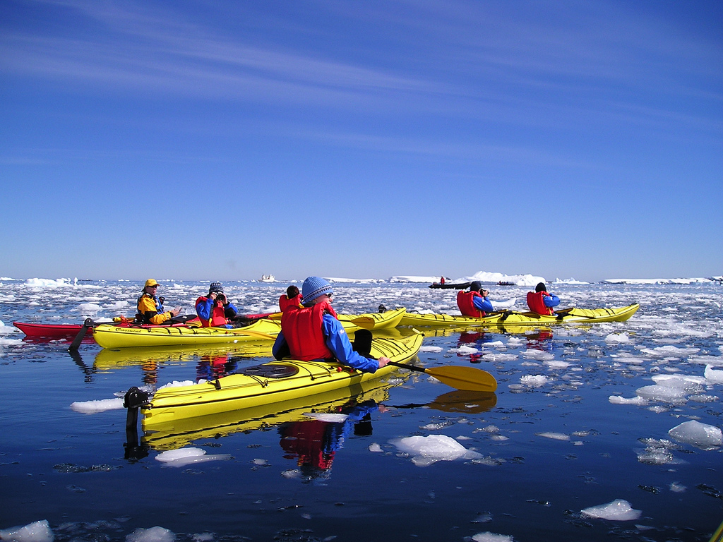 Group of people kayaking through ice in Antarctica. 