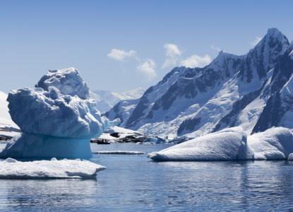 unique iceberg formation in calm bay with snowy mountains in background in Antarctica) 
