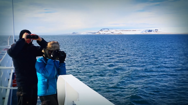 Two people with binoculars on an Arctic cruise.