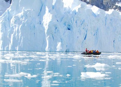 zodiac with tourists in front of a glacier in Antarctica) 